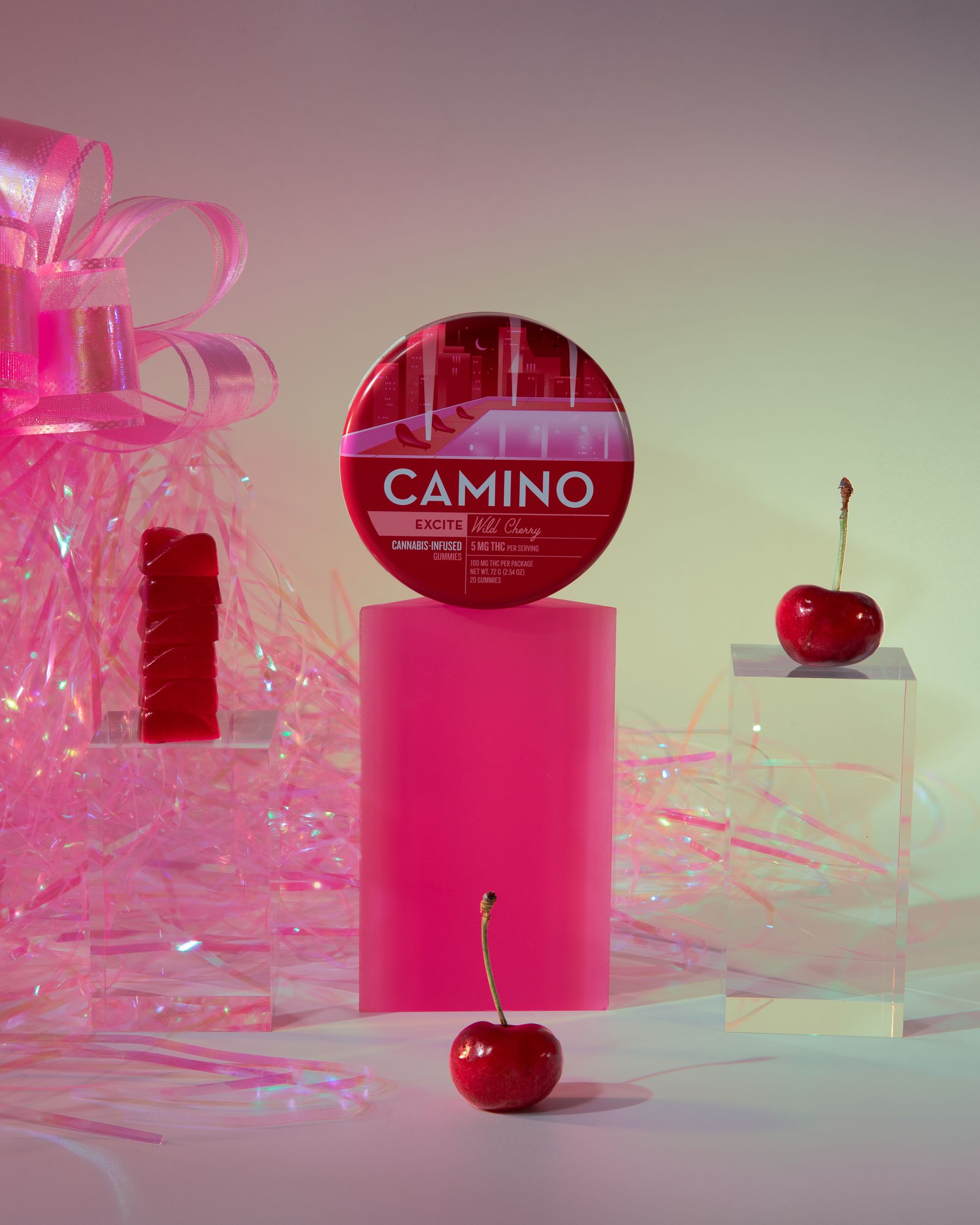 Camino tin on a hot-pink plinth with cherries and pink cellophane ribbon.