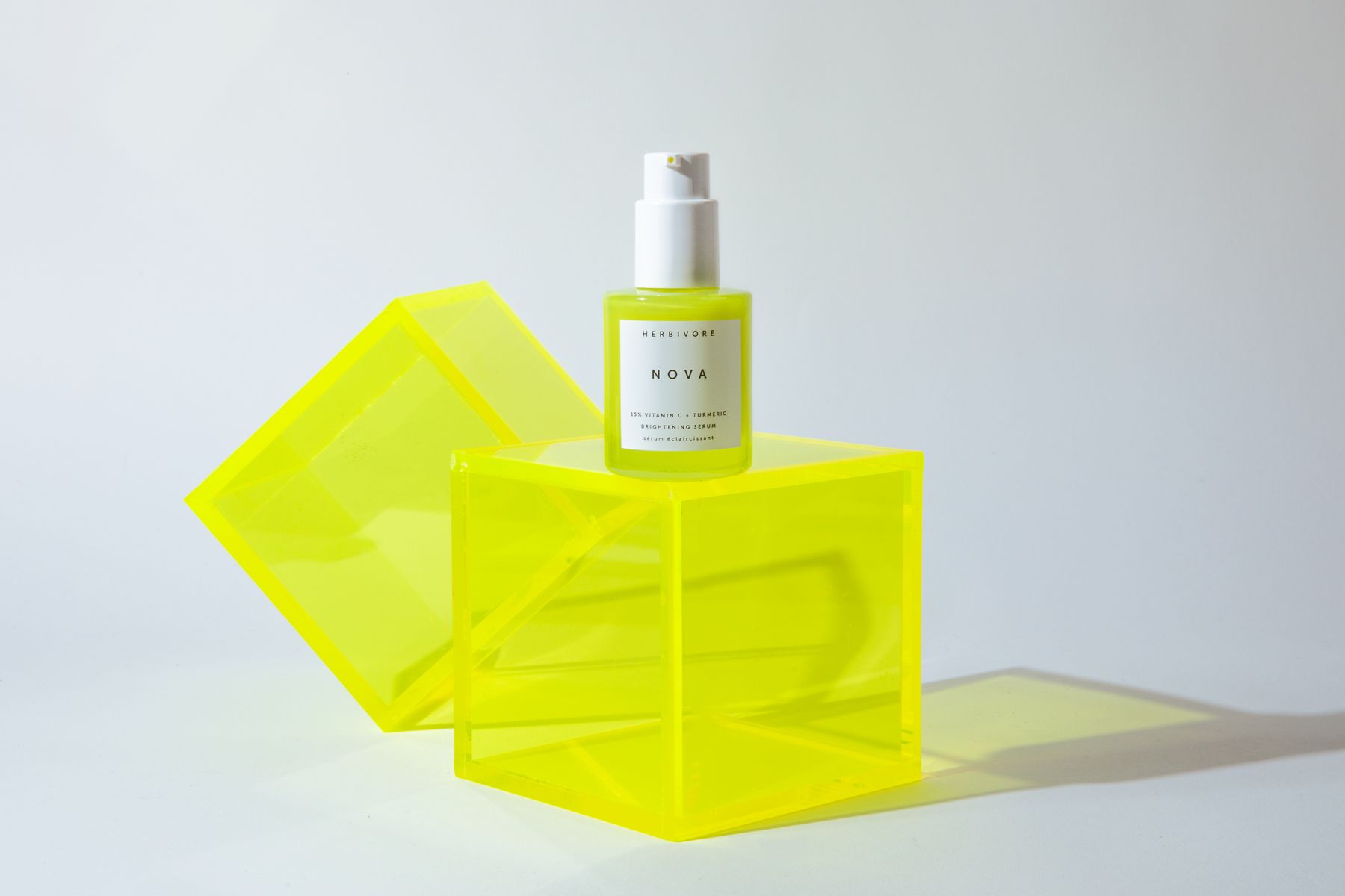 Small serum dropper bottle on neon-yellow acrylic cubes.
