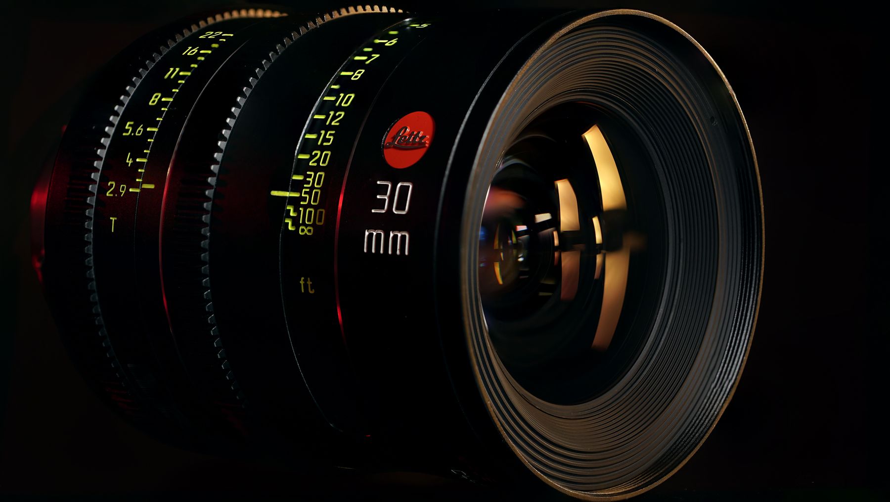 Cine primes with red badge (30mm) and warm internal reflections on dark.