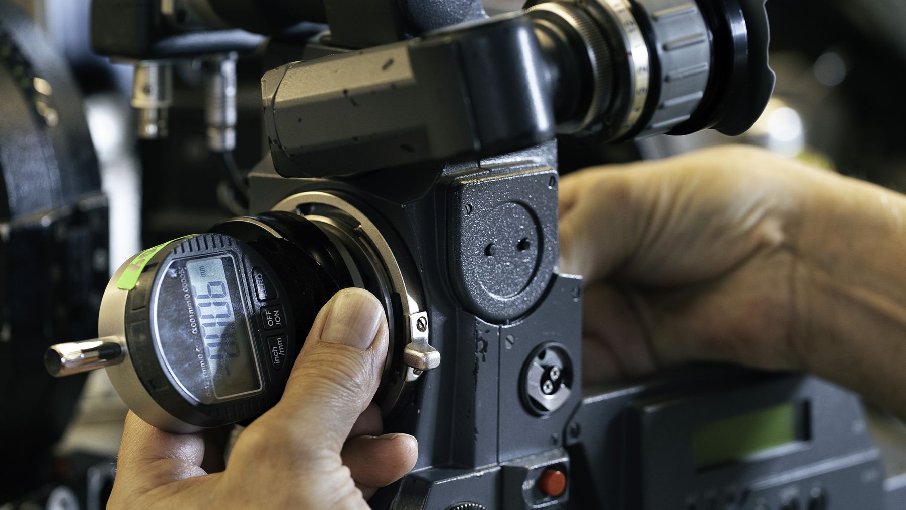 Technician adjusting a lens gauge on a camera.