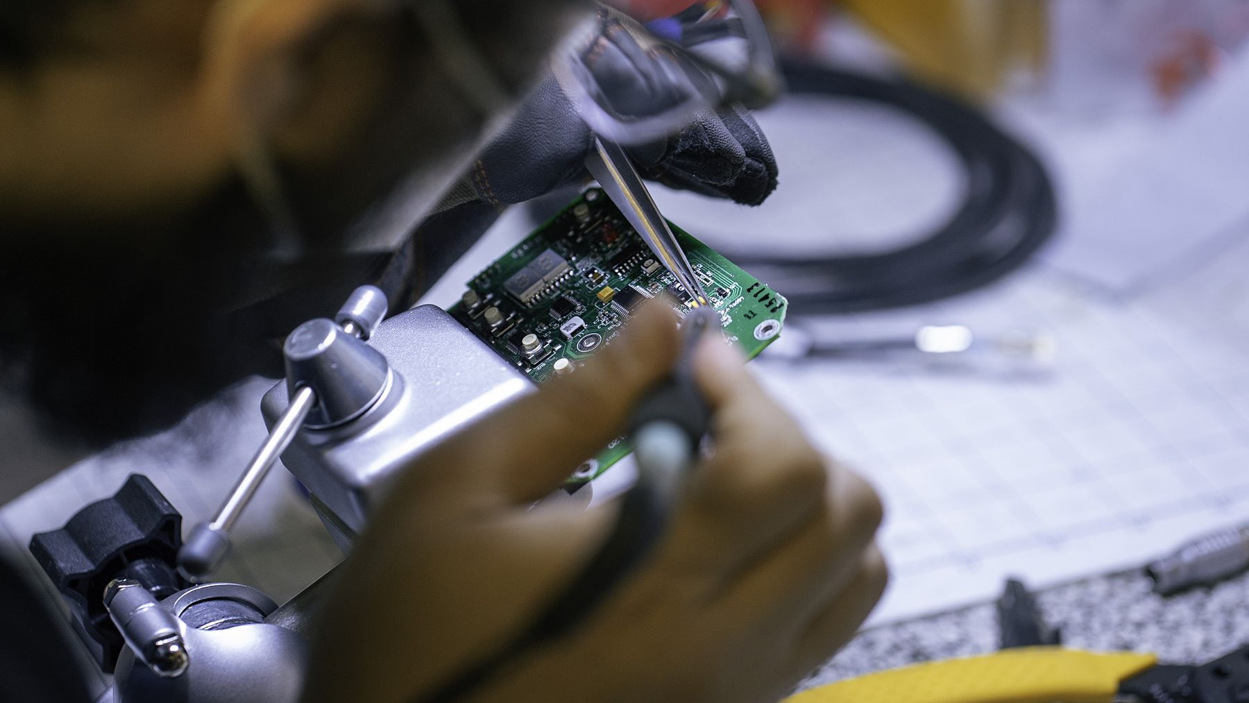 Technician soldering a circuit board (hands, workshop).