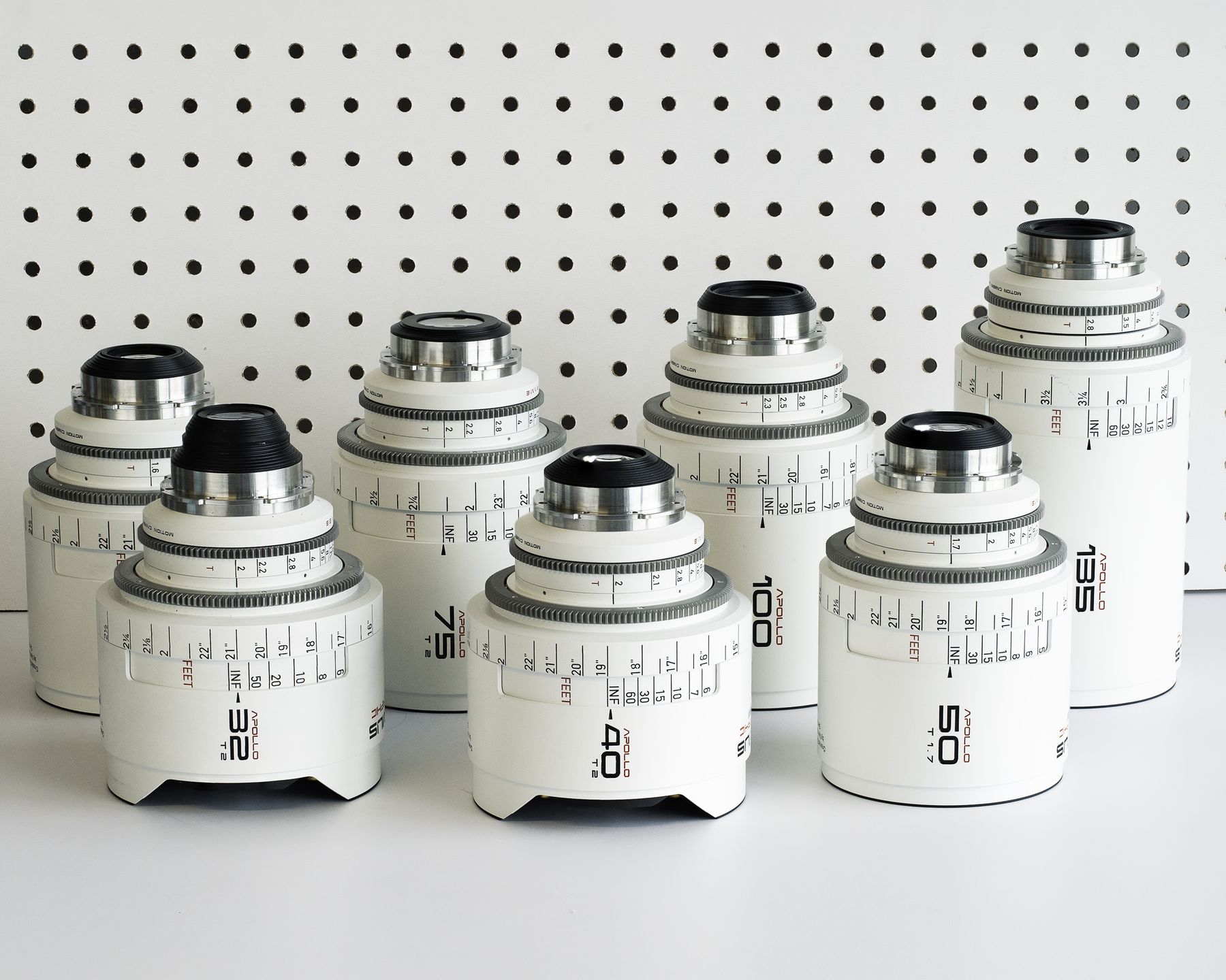 Set of white-bodied cine primes in front of a white pegboard.